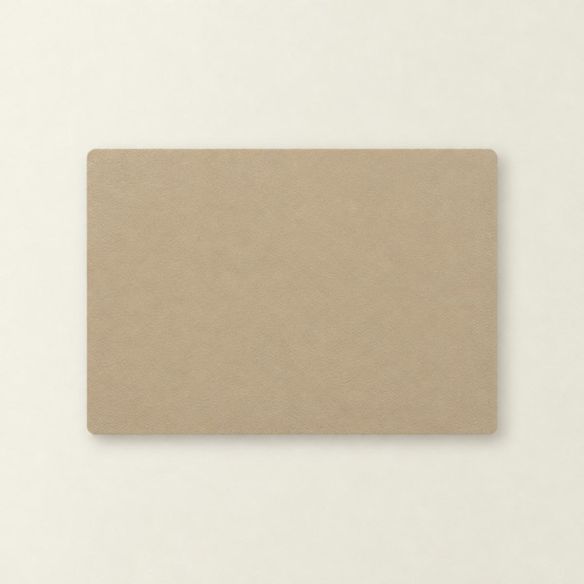 Een rechthoekige placemat van beige kunstleer met afgeronde hoeken, plat neergelegd op een lichte ondergrond voor een strakke en moderne uitstraling.