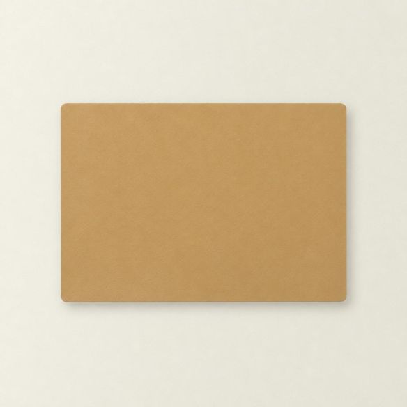 Een rechthoekige placemat van kunstleer in de kleur desert taupe met afgeronde hoeken, plat afgebeeld op een lichte, neutrale ondergrond.