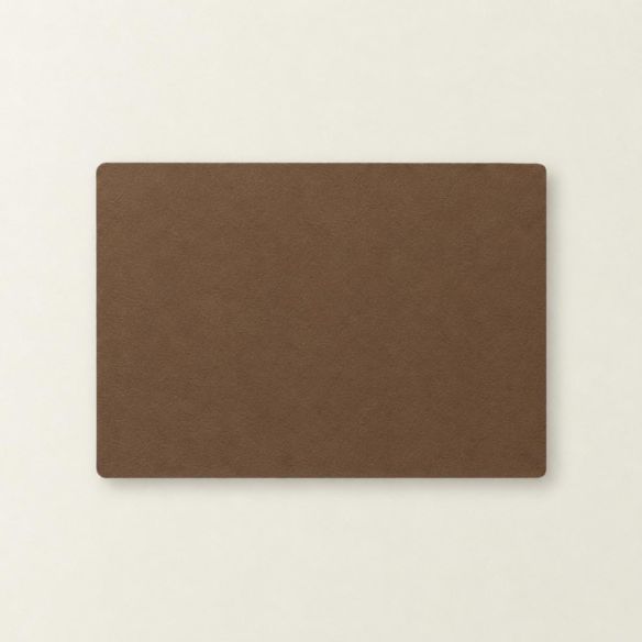 Een rechthoekige placemat van mokkakleurig kunstleer met afgeronde hoeken, plat gepresenteerd op een effen witte ondergrond voor een strakke uitstraling.
