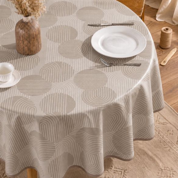 Rond beige tafelzeil met een modern patroon van cirkels en lijnen, gedekt op een tafel met een wit bord, bestek en een decoratieve vaas.