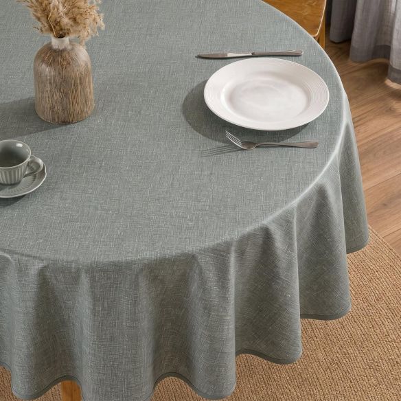 Rond donkergroen tafelzeil Mandara met een subtiele textuur, gedrapeerd over een ronde tafel met servies, een vaas en bestek in een eetkamer.