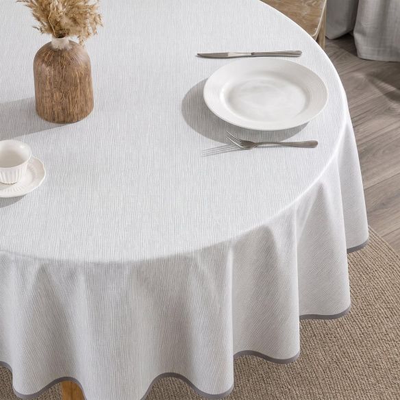 Rond grijs tafelzeil Namaste Earl Grey met subtiel lijnenpatroon, gedekt op een ronde tafel met een wit bord, bestek en een decoratieve vaas.