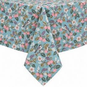 Gecoat tafellinnen met een digitaal geprint patroon van wilde besjes en bloemen in zachte kleuren op een lichtblauwe ondergrond over een tafel.