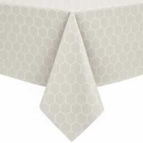 Gecoat tafellinnen in de kleur Piombo wit met een subtiel geometrisch honingraatpatroon, elegant gedrapeerd over de hoek van een tafel.