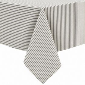 Gecoat tafellinnen Degas Marino met een klassiek verticaal streeppatroon in donkerblauw en beige, elegant gedrapeerd over de hoek van een tafel.