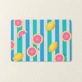 Rechthoekige Placemat Aloha met een vrolijk patroon van roze grapefruit en gele citroenen op een achtergrond van blauwe en witte verticale strepen.
