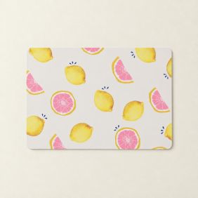 Rechthoekige Placemat Summer Living met een vrolijk patroon van gele citroenen en roze grapefruitpartjes op een lichtbeige achtergrond.