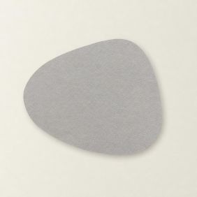Een grijze Placemat Floris met een organische, asymmetrische vorm en een subtiele leerachtige textuur, plat gefotografeerd op een lichte ondergrond.