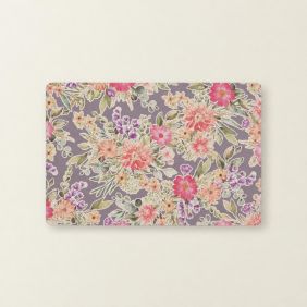 Rechthoekige grijze placemat met een kleurrijk bloemmotief van roze, oranje en paarse bloemen en groene bladeren op een effen lichtgrijze achtergrond.
