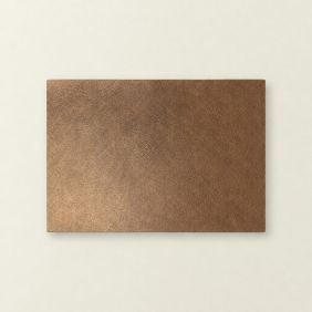 Rechthoekige placemat Ava in koperkleur met een subtiele leerachtige textuur, plat neergelegd op een lichte ondergrond voor een stijlvolle tafeldekking.