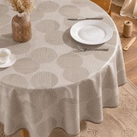 Rond beige tafelzeil met een modern patroon van cirkels en lijnen, gedrapeerd over een ronde tafel met serviesgoed in een sfeervolle setting.