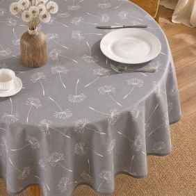 Rond grijs tafelzeil met wit paardenbloemmotief, gedekt op een ronde tafel met servies en een vaas met pluizen, voorzien van een molton rugzijde.